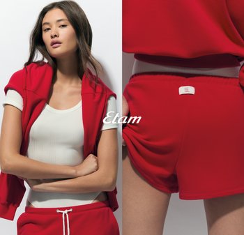 Rode activewear set bestaande uit een strakke witte geribbelde tanktop en losse rode shorts. De shorts hebben een label op de achterkant van de tailleband.