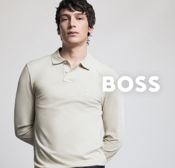 Junger Mann in einem hellbeigen Langarm-Polohemd mit "BOSS"-Logo, steht vor einem schlichten hellen Hintergrund.