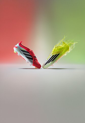 Chaussures de football Adidas rouges et jaune néon se faisant face, flottant sur un fond dégradé rouge et vert.
