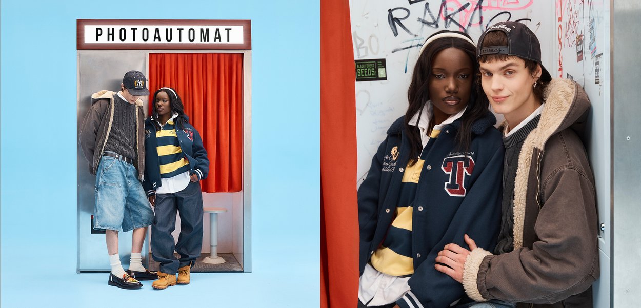 Two young people standing close to a photo booth with red curtains, dressed in casual streetwear and looking at each other.