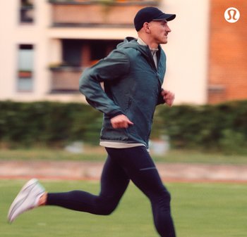 Lichtgewicht groene sportjack, zwarte leggings en witte hardloopschoenen. Strakke stoffen, ontspannen pasvorm en gestroomlijnd ontwerp voor beweging.