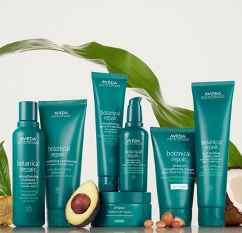 Set van acht Aveda haarverzorgingsproducten in groene verpakkingen, met verschillende vormen en maten, voorzien van witte tekstlabels en natuurlijke ingrediënten op de voorgrond.