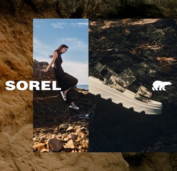 Frau in schwarzem Kleid und SOREL Camouflage-Sandalen sitzt am felsigen Ufer neben einer Nahaufnahme einer Camouflage-Sandale auf dunklen Steinen.