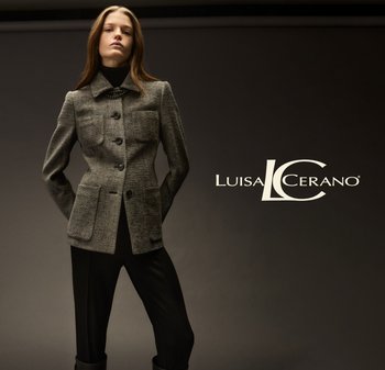 Tailored gray tweed jacket with a collar, four front pockets, and black buttons, paired with dark pants and set against a neutral background.