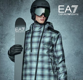 Chaqueta de esquí con un patrón de cuadros en azul y gris, que presenta un cuello alto, material impermeable y acentos negros. Complementada con un casco negro y guantes.