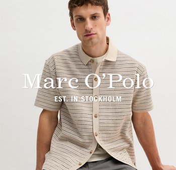 Mężczyzna ubrany w beżową koszulę na krótki rękaw w paski, noszoną na t-shirt, siedzący na tle jasnego, jednolitego tła.