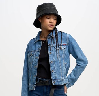 Lichtblauwe denimjack met een klassieke snit, voorzien van borstzakken, metalen knopen en een kraag. Draagt over een zwart top.