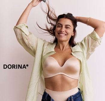 Reggiseno beige imbottito con una scollatura profonda a V, indossato sotto una camicia verde chiaro semi-trasparente. La modella ha i capelli scuri che le cadono sulle spalle, sorridendo.