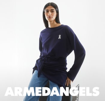 Marineblaues Langarmshirt mit einem weißen Band-Graphic auf der Brust, kombiniert mit hellblauen Jeans. Der Stoff wirkt weich und hat eine lockere Passform.