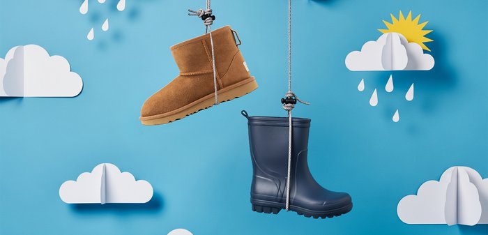 Botte courte en daim marron et botte de pluie en caoutchouc bleu suspendues sur un fond bleu avec des nuages en papier et des gouttes de pluie.