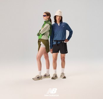 Deux personnes se tiennent côte à côte. La femme porte une veste verte et crème, un short blanc et des lunettes de soleil. L'homme porte une chemise à manches longues bleue et un short noir, tous deux avec des chaussures de sport.