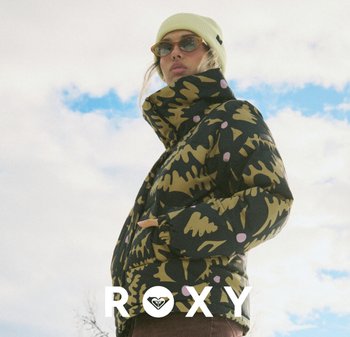 Doudoune avec un motif abstrait noir et vert olive, agrémentée d'accents roses. Associée à un bonnet jaune clair et des lunettes de soleil.