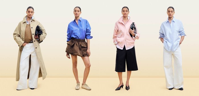 Femme portant une chemise bleue à boutons avec de fines rayures blanches et un pantalon marron à taille froncée, debout devant un fond clair uni.