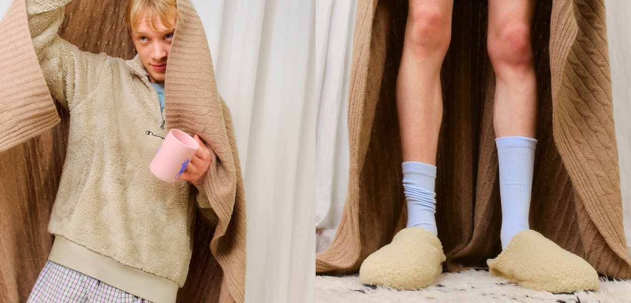 Sweatshirt com fecho éclair em tecido polar na cor bege; manta comprida castanha em malha a condizer. O modelo usa meias azul-claro e chinelos amarelos felpudos com biqueira redonda.