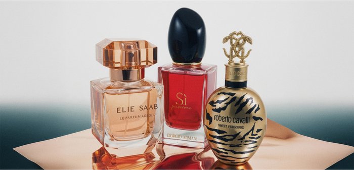 Trois bouteilles de parfum : une bouteille hexagonale transparente contenant un liquide pêche clair, une bouteille rectangulaire avec un liquide rouge, et une bouteille ovale dorée avec un motif léopard noir.