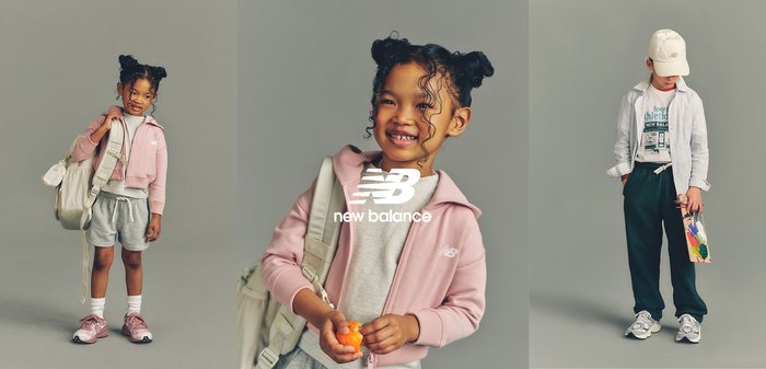 Deux enfants en tenue de sport New Balance posent devant un fond uni ; l’un sourit et tient un fruit, l’autre tient un sac et regarde vers le bas.