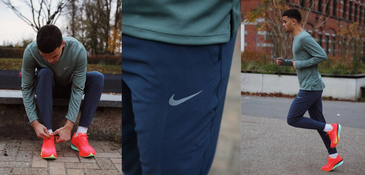 Man die een teal T-shirt met lange mouwen en marineblauwe broek draagt, met neonoranje hardloopschoenen, bezig met het strikken van zijn veters, een close-up van het logo op de broek, joggend in de buitenlucht.