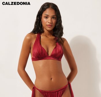 Ensemble bikini rouge avec un design à col licou, des bonnets plissés et un bas à nouer ajustable sur les côtés, fabriqué en tissu lisse et brillant.