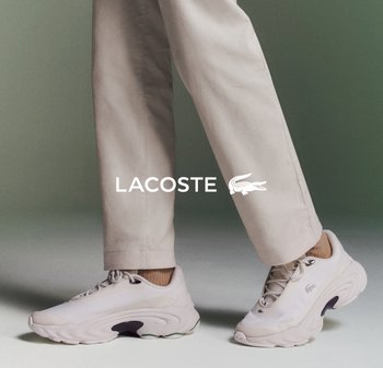 Sneakers Lacoste in beige chiaro con tomaia in mesh testurizzato, design minimalista, suola curva e branding discreto. Abbinati a pantaloni beige.