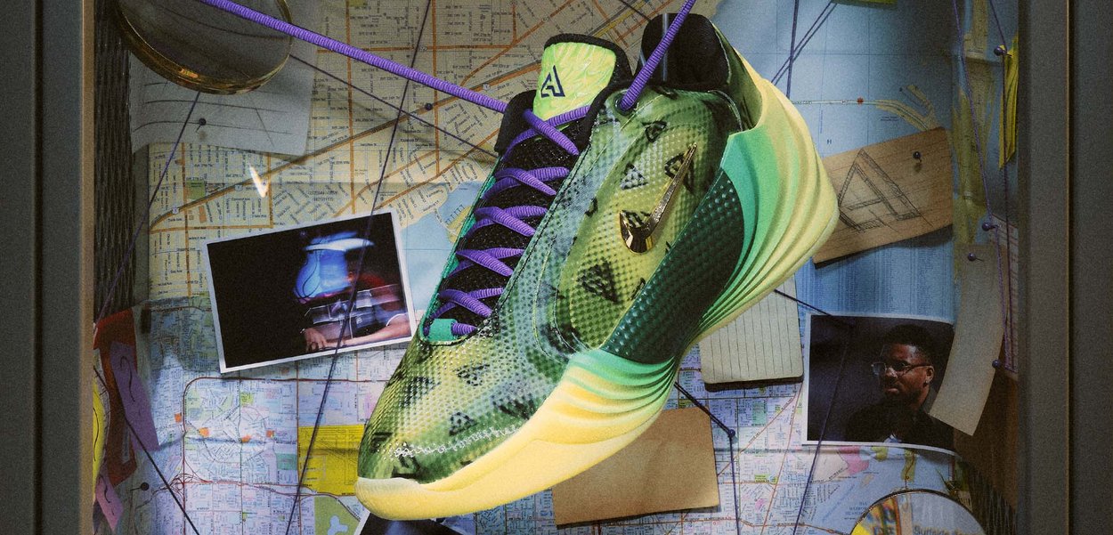 Une chaussure de basket Adidas verte et jaune, avec des lacets violets, est suspendue au-dessus d’un mur couvert de cartes, de notes et de photographies.