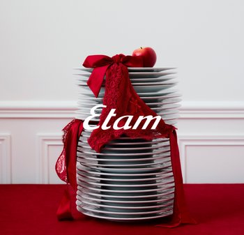 Stapelhaufen weißer Teller mit roter Spitzenunterwäsche und Schleife darauf, obenauf ein roter Apfel, Text "Etam" über die Mitte.