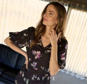 Zwarte bloemenjurk met puffmouwen, V-hals en een gestructureerd patroon. Decoratieve bloemaccenten in tinten paars en wit.