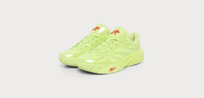 Paire de chaussures de sport jaune-vert vif avec logos rouges et design à lacets sur un fond gris clair uni.