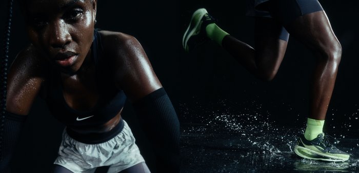 Sweaty athlete in black sportswear and white shorts pauses during intense workout as water splashes under neon-shoed foot in motion.