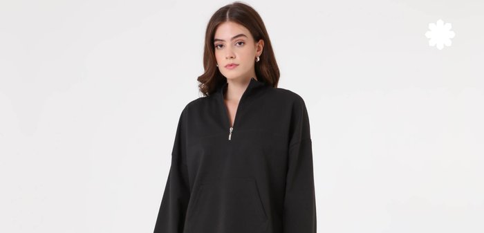 Sweat-shirt noir zippé avec des manches longues et larges et une poche avant. Tissu doux avec une coupe décontractée et un design minimaliste.