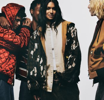 Cuatro personas visten ropa exterior diversa. Las características notables incluyen una chaqueta acolchada roja, una sudadera marrón con cremallera y un camisa beige con botones.