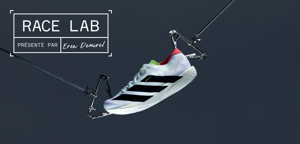 Chaussure de sport blanche avec des rayures noires, des accents rouges et verts. Équipée d'un dessus texturé et d'une semelle légère estampillée "LIGHTSTRIKE PRO."