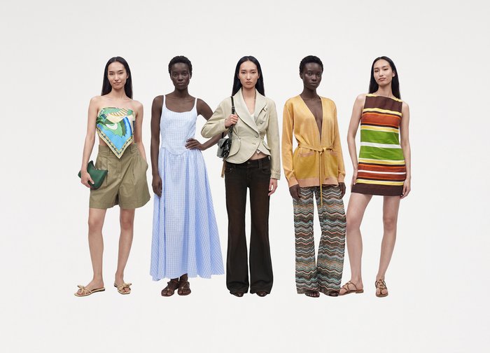 Cinq femmes sont debout en file, chacune portant des tenues d'été différentes, comprenant des robes, des pantalons, un blazer et des tissus à motifs. Fond blanc.