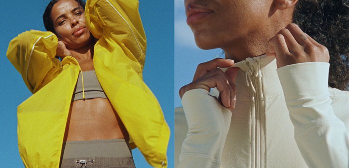 Femme portant une veste jaune vif sur un soutien-gorge de sport gris et un pantalon, posant les mains derrière la tête devant un ciel bleu clair.