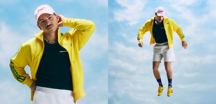 Homme en veste jaune et short blanc posant et sautant devant un ciel bleu avec des nuages.