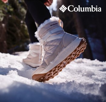 Person, der beigen Columbia-Winterstiefel mit fellgefütterter Innenseite trägt, geht auf Schnee in einer bewaldeten Außenumgebung.