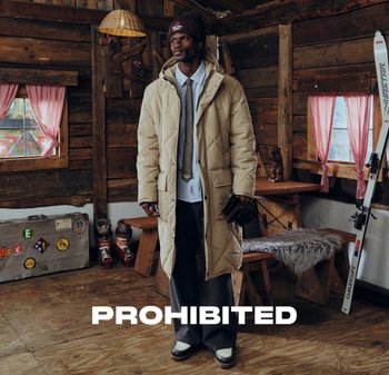 Beige quilted long coat with a hood, layered over a light blue shirt and gray tie. Dark pants and brown shoes complete the look.