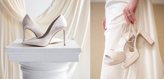 Paar weiße, spitze High-Heels, präsentiert auf einem weißen Sockel mit cremefarbenen Vorhängen im Hintergrund.