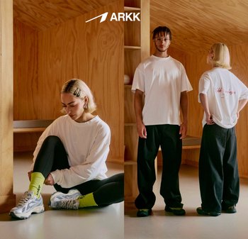 Unisex oversized hvite t-skjorter, svarte avslappede bukser, grønne sokker med aksent og sporty grå joggesko. Minimalistisk innendørs setting.