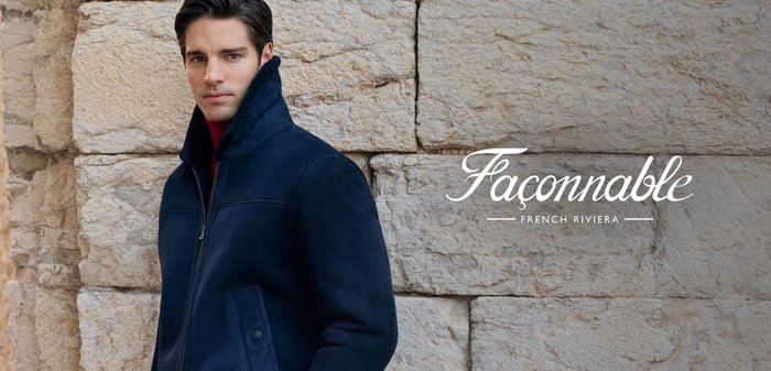 Veste zippée en daim bleu marine avec un col montant, présentant une texture lisse et un design minimaliste, associée à un pull à col roulé rouge.