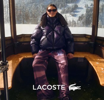 Puffy purple jacket with a brown collar, paired with gradient purple pants featuring pink accents. Worn with black sunglasses in a wooden setting.