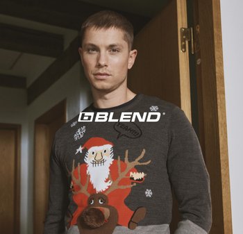 Grauer Strickpullover mit bunten Weihnachtsmotiven von Weihnachtsmann und Rentier, mit 3D-Elementen, darunter eine braune Bommelnase.