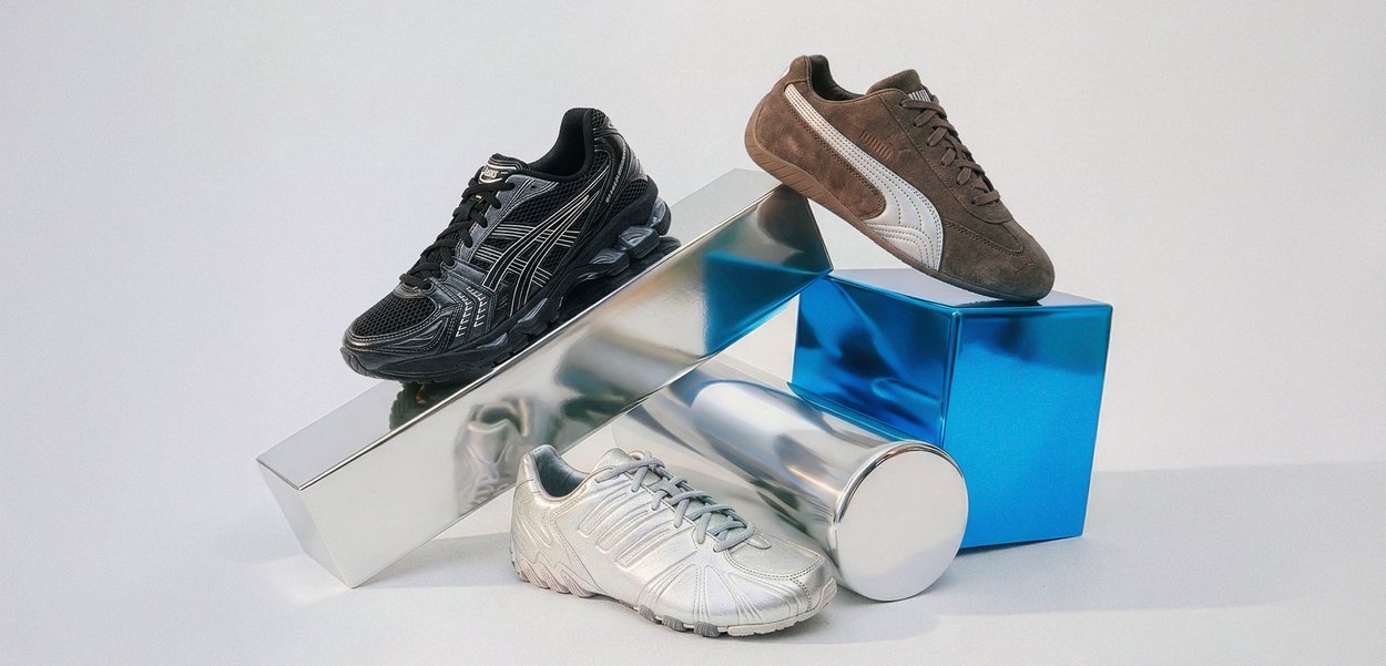 Trois chaussures de sport en noir, marron et argent disposées sur des formes géométriques métalliques brillantes sur un fond blanc.