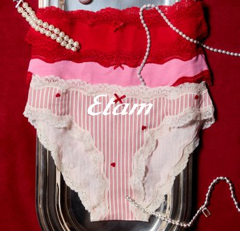 Drei Paare Spitzen-Unterwäsche für Damen in Rot, Pink und Weiß mit Herzmustern, stilvoll arrangiert mit Perlen- und Perlenketten auf einem metallischen Tablett.