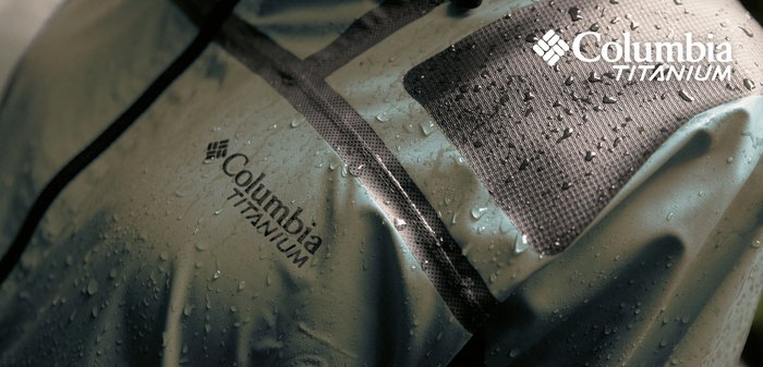 Water droplets on gray Columbia Titanium waterproof jacket fabric with taped seams and logo branding.