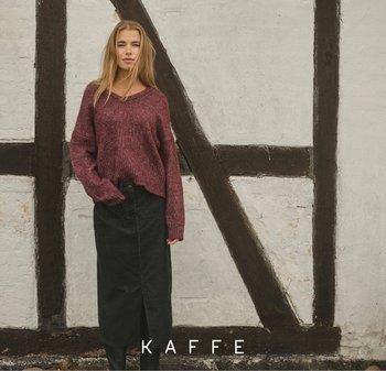 Burgundin värinen neulepaita V-kaula-aukolla ja lasketuilla harteilla, yhdistetty mustan denimpituisen hameen kanssa, jossa on etuhalkio. Teksturoitu tausta.
