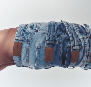 Helle blaue Jeansshorts mit mehreren Taschen und braunen Leder-Logos; an der Taille mit einem verdrehten Riemen gerafft.