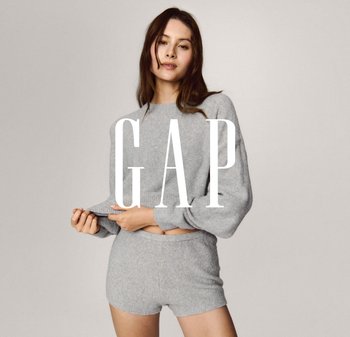 Lysegrå kort trøje med ribbet kant og matchende teksturerede shorts. Modellen holder i trøjens kant; blødt, behageligt stof med minimal pynt.