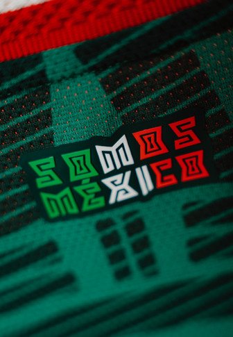 Zielony materiał z teksturowanym wzorem; łatka zawiera napis "SOMOS MEXICO" w czerwonych, białych i zielonych kolorach, obrysowany dla lepszej widoczności.
