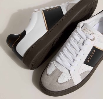 Sneaker bianchi e grigi con tomaia in pelle liscia, dettagli in suede, sezioni perforate, una striscia laterale nera e logo dorato.