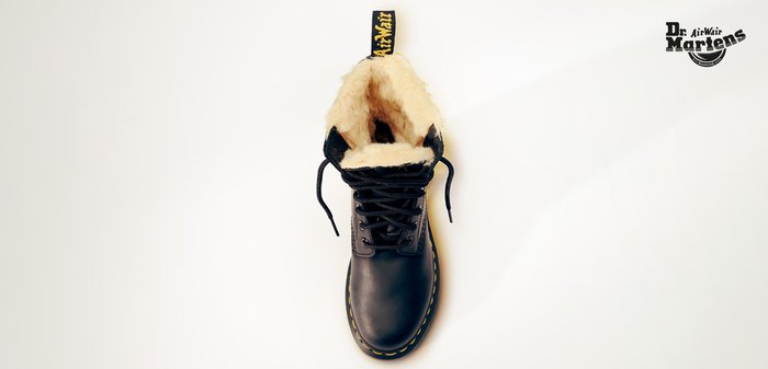 Bottine en cuir noir avec une doublure en fourrure beige, bout rond, surpiqûres jaunes et lacets noirs. Dotée d'une languette jaune marquée de la marque.